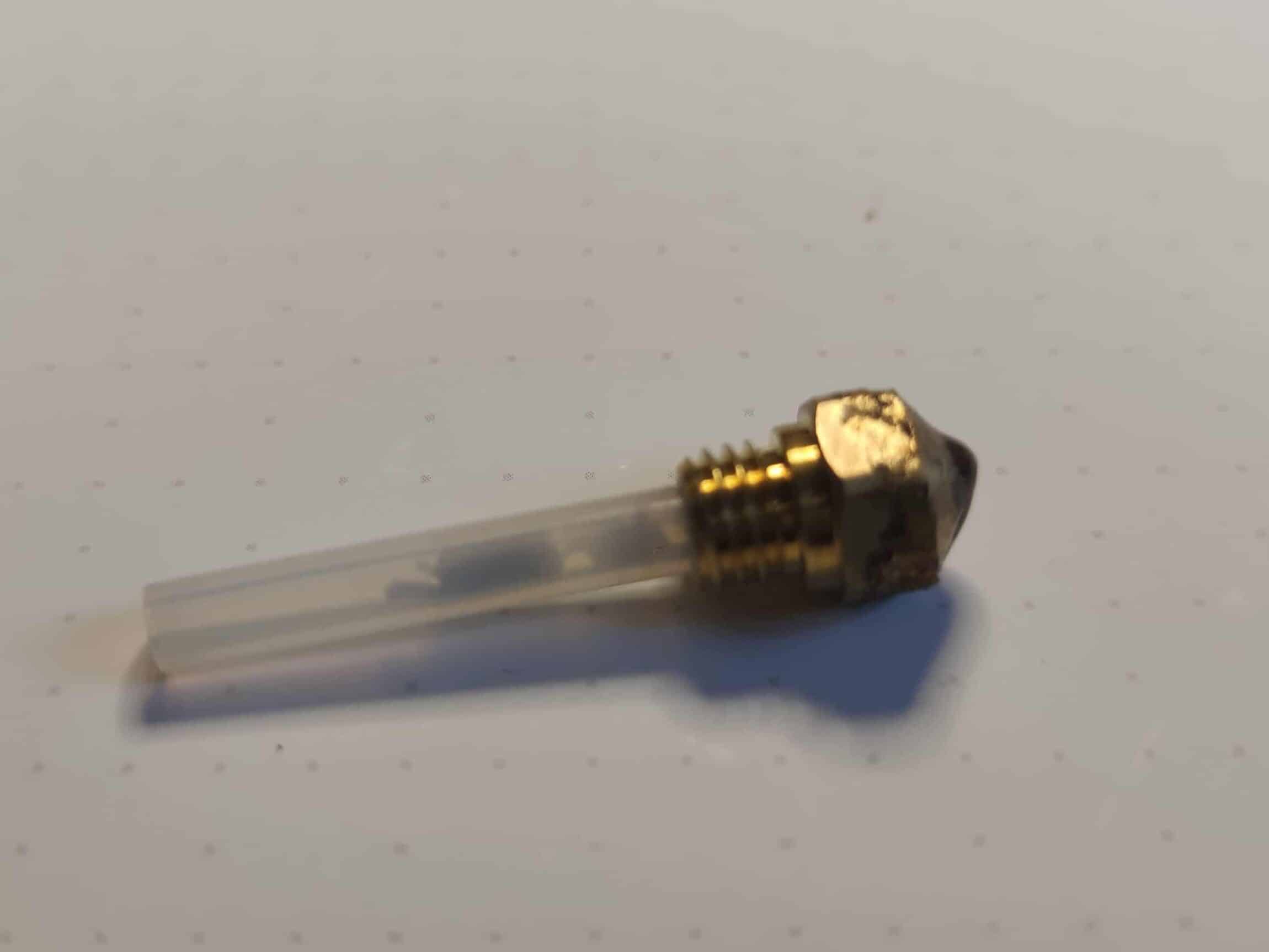 Ein etwas ramponierter Nozzles mit seinem Schlauch, in dem man Filament-reste erkennt.